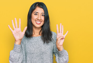 Beautiful asian young woman wearing casual clothes showing and pointing up with fingers number nine...