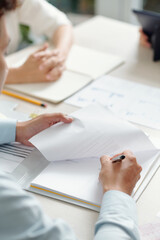 Hands of entrepreneur signing every page of important document at office table