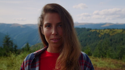 Portrait of laughing woman face looking at camera in green mountains