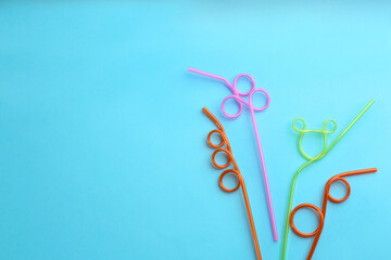 Colorful plastic drinking straws on light blue background, flat lay. Space for text