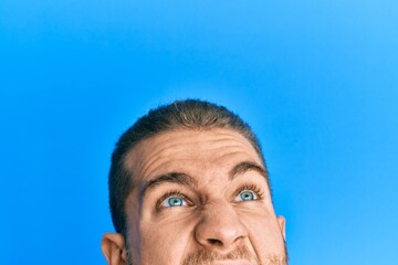 Young caucasian man showing head and half face angry and mad screaming frustrated and furious, shouting with anger looking up.