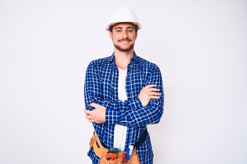 Young handsome man weaing handyman uniform happy face smiling with crossed arms looking at the camera. positive person.