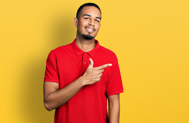 Young african american man wearing casual polo smiling cheerful pointing with hand and finger up to...
