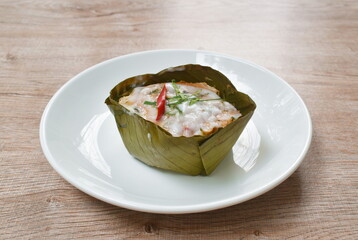 steamed fish with curry paste in banana leaf tray on plate