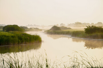 Fototapeta na wymiar Sunrise in a light fog on a small river