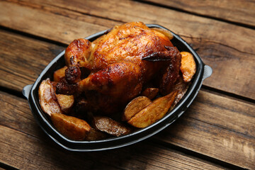 Delicious grilled chicken with potato in plastic container on wooden table. Food delivery service