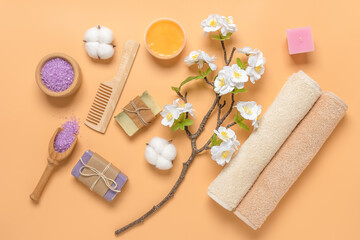 Spa composition on a pastel yellow background. Health and beauty concept. Cosmetics, terry towels and cherry blossoms (artificial). Top view.