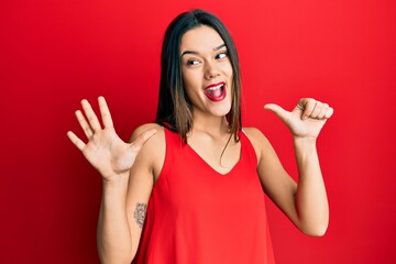 Young hispanic girl wearing casual style with sleeveless shirt showing and pointing up with fingers...