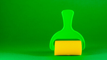 bright construction roller for decorative works on a green paper background. Minimalistic creative composition, one item