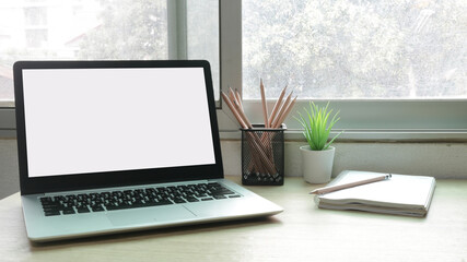 Laptop computer with white blank screen on desk in workspace and copy space concept