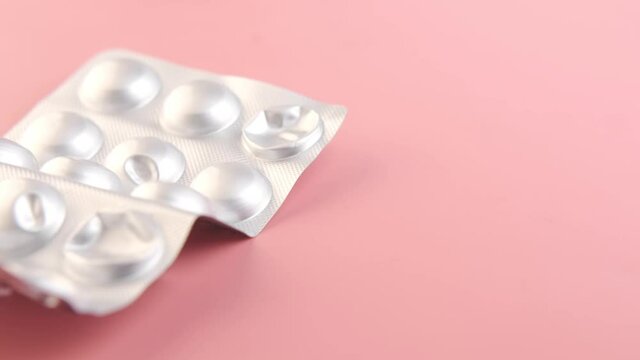 Close up of pills of blister pack on pink 