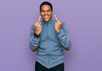 Young handsome hispanic man wearing casual sweatshirt showing middle finger doing fuck you bad expression, provocation and rude attitude. screaming excited