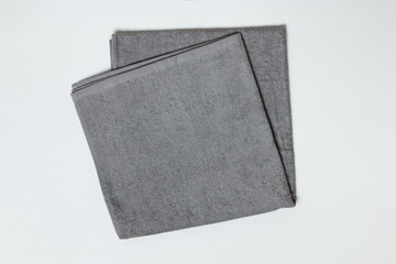 Gray folded towel on a white background. Close-up flat lay top view.