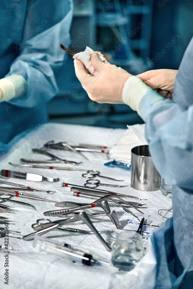Poster hands of a team of surgeons close-up in the operating room during the operation, sterile instruments