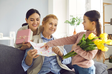 Surprise for the dearest. Little daughter and her adult mother congratulate the grandmother on...
