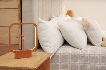 Modern lamp on nightstand near bed in hotel