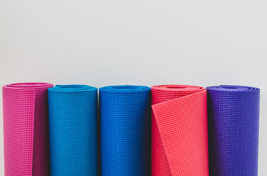 Close Up Of Colourful Rolled Yoga Mats In A Yoga Studio By A White Wall Background With Copy Space