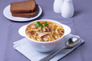 Soup with mushrooms, chicken and noodles in a white plate. Traditional Russian dish. Close-up.