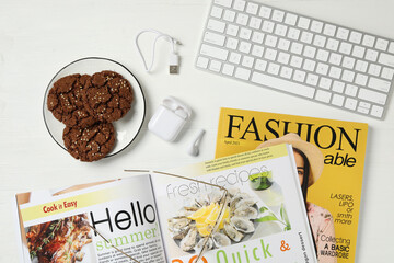 Workplace with modern magazines on white wooden table, flat lay