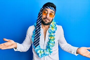 Young hispanic businessman wearing party funny style with tie on head clueless and confused...