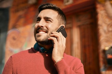 Young hispanic man smiling happy talking on the smartphone at the city.