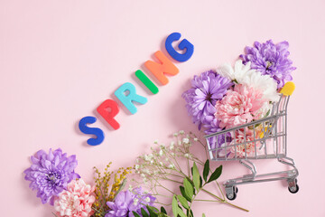 ishopping troley, nscription spring in flowers on a pink background top view spring mood concept