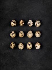 Geometric shapes from quail eggs on a black textured background. Square.