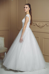 Fototapeta premium Happy bride in luxury sparkly wedding dress posing in studio on brown background. Marriage concept.