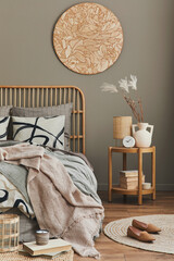 Wooden bed in stylish neutral bedroom interior with design furniture, decoration, carpet, book,...