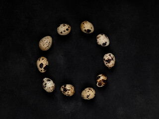 Geometric shapes from quail eggs on a black textured background. A circle