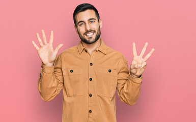 Young hispanic man wearing casual clothes showing and pointing up with fingers number eight while smiling confident and happy.