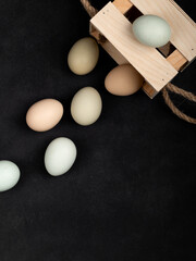 Fresh white chicken eggs in a wooden box, top view, on a black textured background. Healthy eating. Creativity.