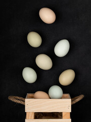 Fresh white chicken eggs in a wooden box, top view, on a black textured background. Healthy eating. Creativity.
