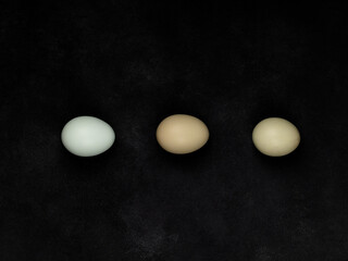 Fresh white chicken eggs, top view, on a black textured background. Creativity.