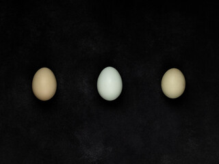 Fresh white chicken eggs, top view, on a black textured background. Creativity.