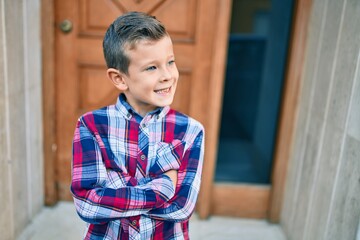 Adorable caucasian boy with crossed arms smiling happy standing at the city.