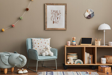 Cozy interior of child room with mint armchair, brown mock up poster frame, toys, teddy bear, plush animal, decoration and hanging cotton colorful balls. Beige wall. Warm kid space. Template.