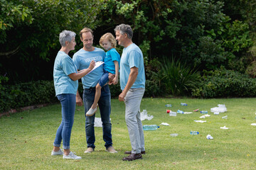 Caucasian senior couple with father and son in volunteer shirts talking in littered field