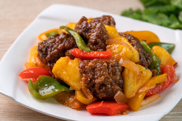 Sweet and sour sauced deep fried pork ribs with chopped pepper and pineapple.