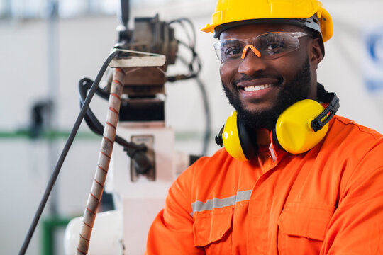 portrait of native american engineer technician wearing safty uniform hand contril automation robot arm welding machine with laptop industrial 4.0 factory background concept