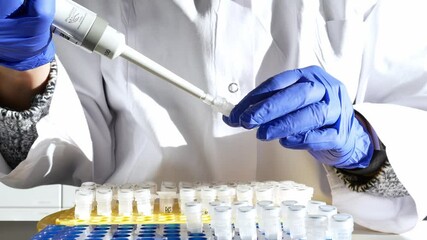 Laboratory researcher or nurse pipets patient sample into a test tube. Genetic engineering or genetic disease screening. Cancer and drug research and science - Powered by Adobe