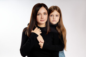 Beauty fashion portrait mother and daughter in a black turtleneck and blue denim skirt. Woman and girl, family