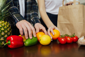 Cropped view of vegan couple disassemble purchases after shopping in kitchen at home.