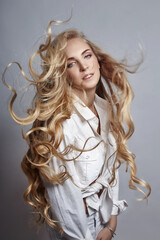Beautiful woman long hair coloring in ultra blond, natural make-up. Stylish hairstyle curls done in...