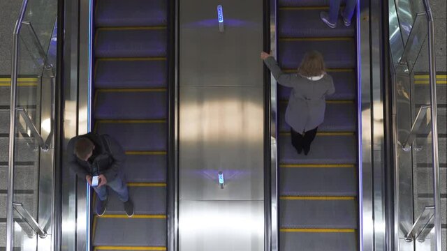 Top down view of moving up escalator. People ride up the escalator up and down in mall.
