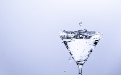 Close-up of water drop falling into a glass on white background
