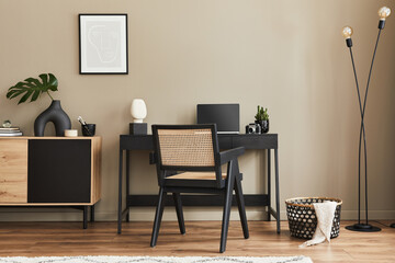 Fancy interior design of home office space with stylish chair, desk, commode, black mock up poster...
