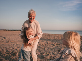 Grandmother plays with granddaughters on the shore