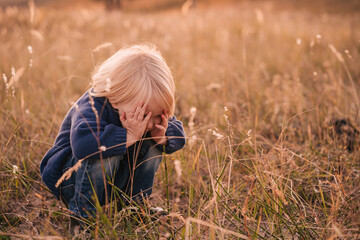 Naklejka na ściany i meble Child hiding in the grass playing hide and seek