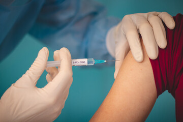 scientist in a protective suit injecting a syringe with a substance against the exact type of...
